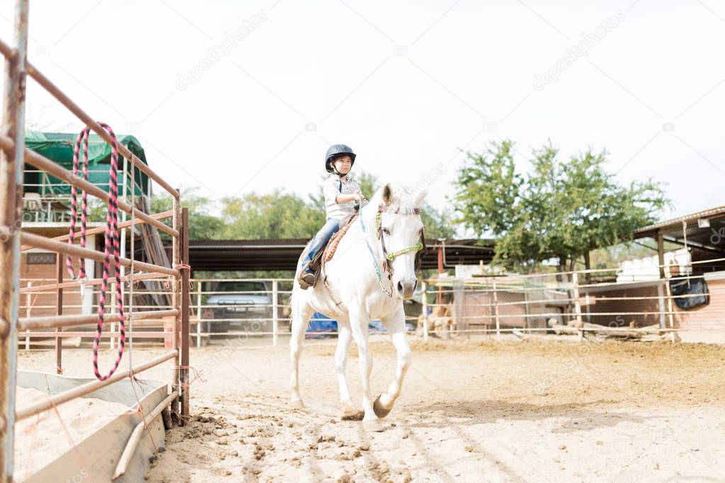 Full length of girl enjoying her leisure time by riding a horse at ranch