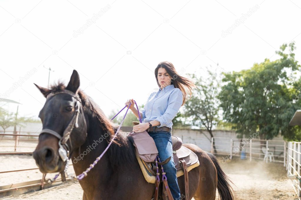 Adventurous woman trying to balance on horse at ranch during sunny day