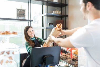 Gülümseyen pazarlamacı baget torba deposundaki erkek müşteriye verilmesi