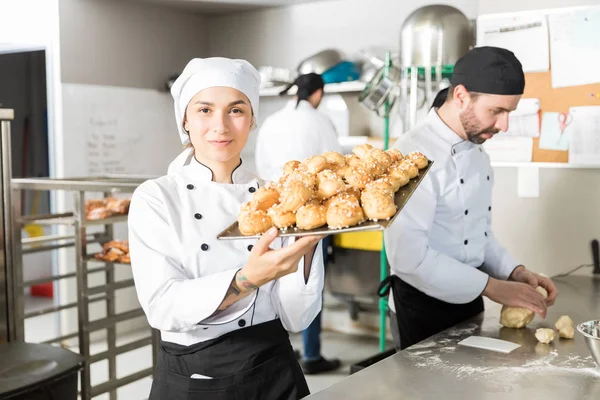 Confident head pastry chef carrying baked chouxs at kitchen counter