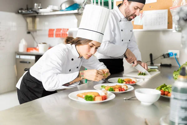 Female Culinary Artist Garnishing Dish Basil Leaves Commercial Kitchen — Stock Photo, Image