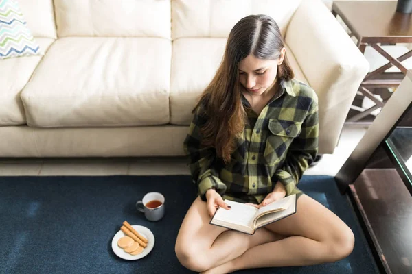 Νεαρή Γυναίκα Καστανά Μαλλιά Διαβάζοντας Μυθιστόρημα Ενώ Ξεκουραζόταν Στον Τάπητα — Φωτογραφία Αρχείου