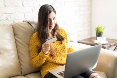Laptop evde kredi kartı ile online alışveriş yaparken iyi görünümlü kadın