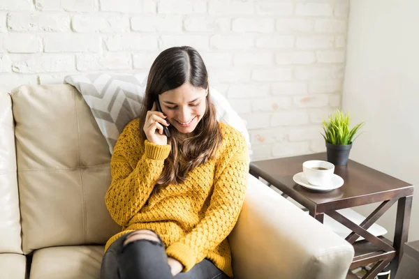 家で携帯電話を使用しながらセーターを着て魅力的な若い女性 — ストック写真