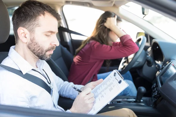 Expert car driving coach giving less marks to sad woman
