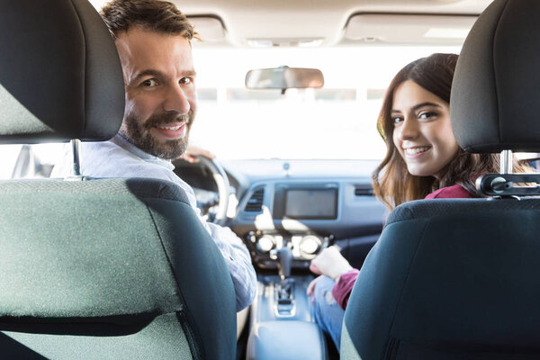 Portrait of beautiful couple sitting in new car looking back and smiling