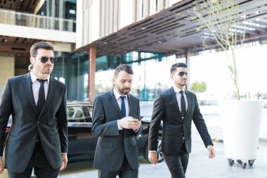 Başkan kampüsünde yürürken korumak takım elbiseli kişisel korumaları