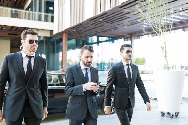 Personal bodyguards in suits protecting president while walking at campus