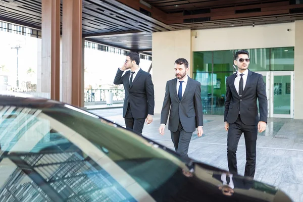 富有的商人与聪明的看着的保镖走向汽车 — 图库照片