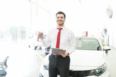 Beyaz araba showroom karşı Pano tutarak yeni araba anahtarları gösterilen mutlu araba satıcısı