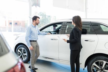 Meraklı yetişkin istemci yeni araba modeli showroom açıklayan pazarlamacı süre bakarak orta
