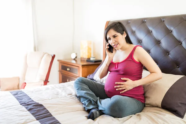 Mid Adult Woman Labor Pain Calling Ambulance While Sitting Bed — Stock Photo, Image