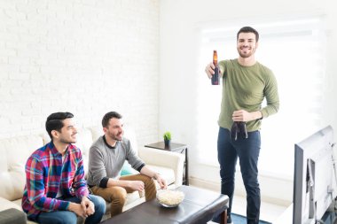 Bira şişeleri evde Tv izlerken arkadaşlar tarafından tutan çekici Latin erkek
