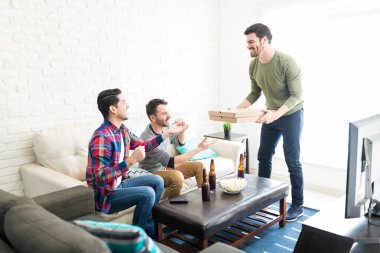 Oturma odasında Tv izlerken arkadaşlar veren pizza kutusu genç yakışıklı adam