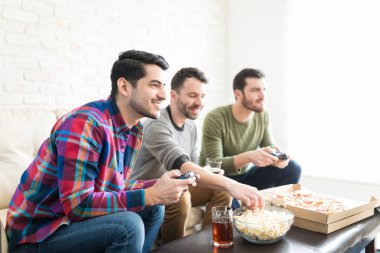 Gülümseyen iyi görünümlü adam oyun oynarken konsol arkadaşlar evde parti