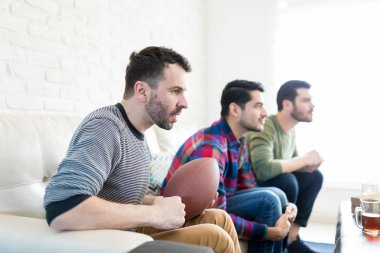 Odaklı arkadaşlarınızla evde Tv izlerken Amerikan futbolu tutan orta yetişkin adam