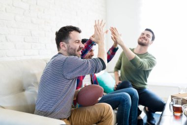 Skor kutluyor ve Amerikan futbolu evde izlerken yüksek beş veren erkek hayranları