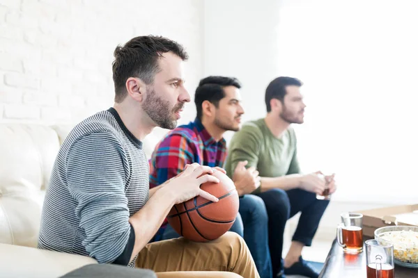 Oturma odasında otururken basketbol maçı izlerken sporseverler