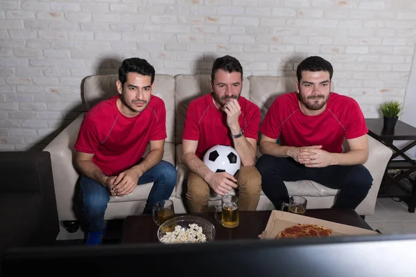 穿着红色球衣的担忧朋友在家里观看最艰苦的足球比赛 — 图库照片