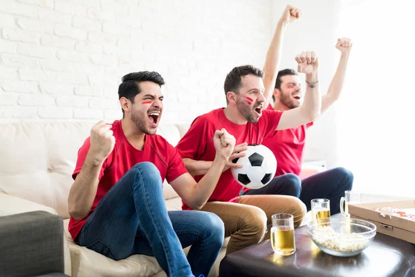 Přešťastný Přátelé Fotbalovým Míčem Ukazující Jejich Nekontrolovatelné Radost Doma — Stock fotografie