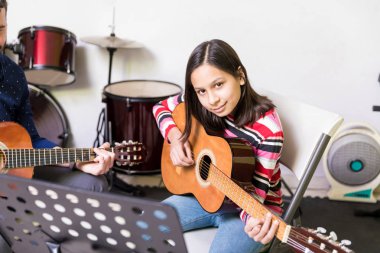 Sağ ve sol elinde gitar sınıfı tekniği öğrenme gülümseyen genç kız