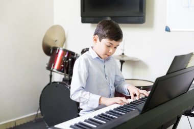 Sevimli çocuk okulda müzik dersinde elektrik piyanoda pratik