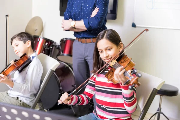 多民族の子供たちが教室に座ってバイオリンを弾くことを学ぶ — ストック写真