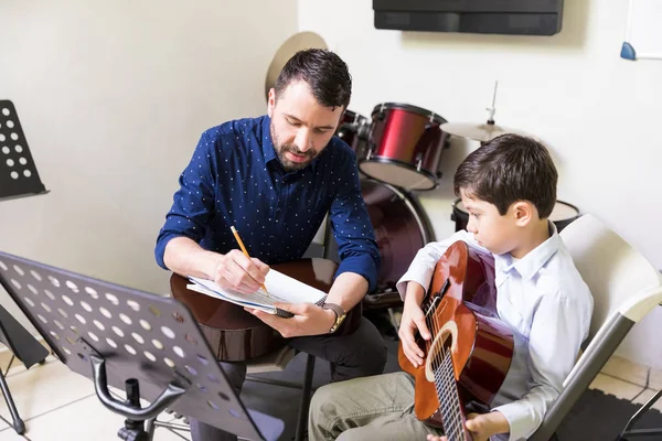 スマートの音楽教師の学生学校でギターを演奏する音符を教える — ストック写真