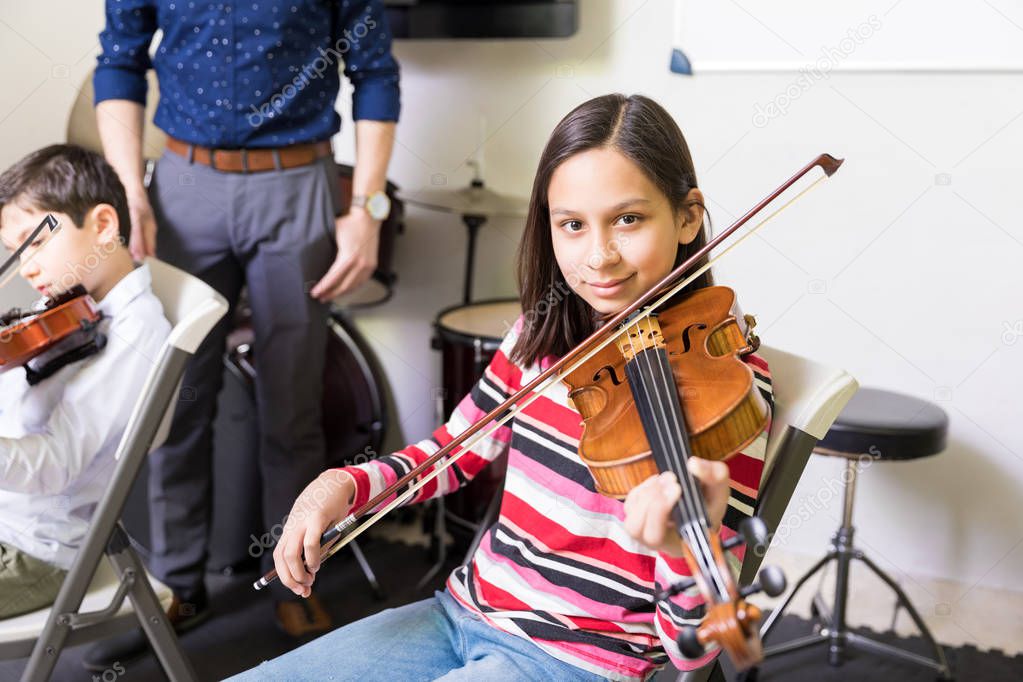 Portrait of girl practicing to improve violin tone in music school