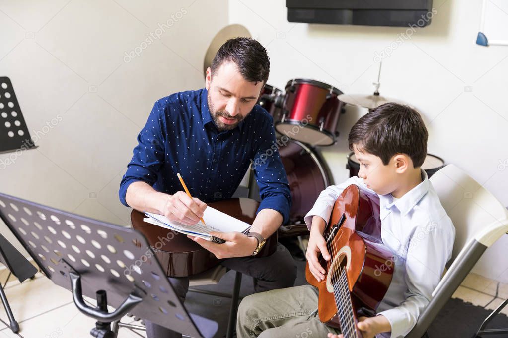 Smart music tutor teaching musical notes to student playing guitar in school