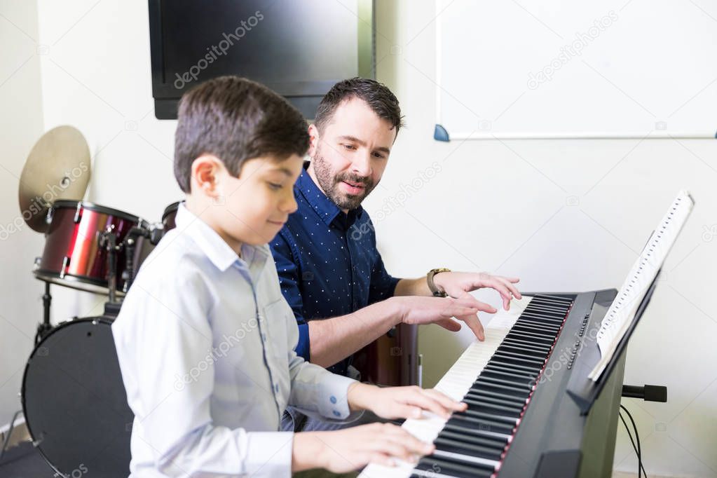 Hispanic instructor developing kid's piano skill in music academy
