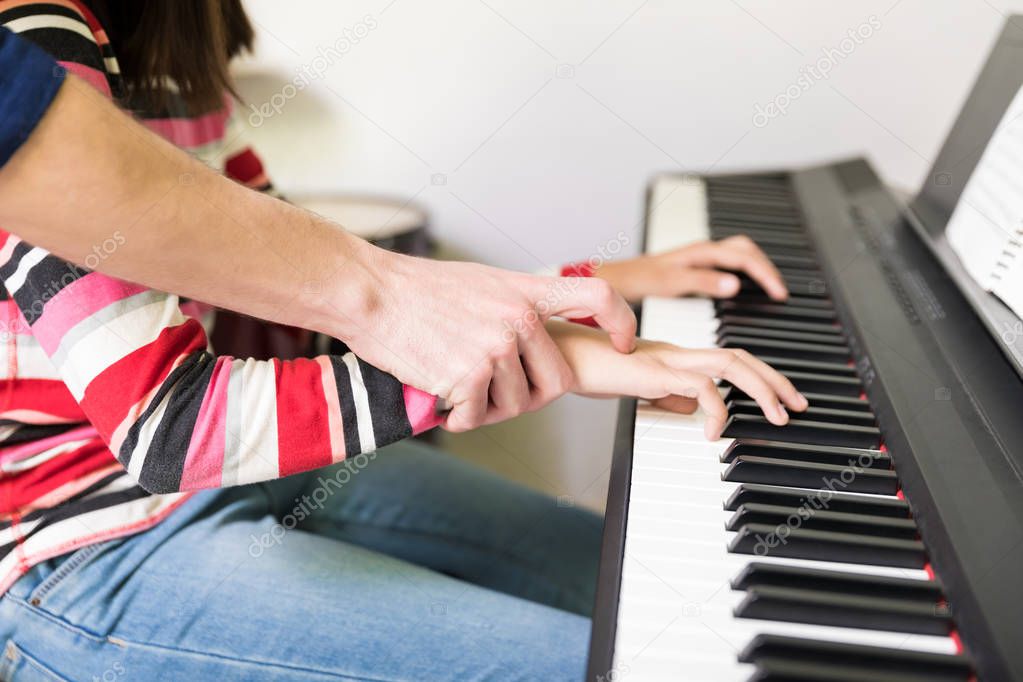 Tutor giving electric piano lessons to teen girl in extracurricular class at school
