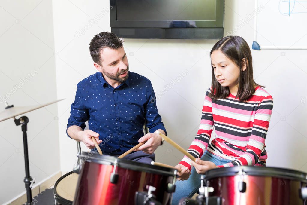 Expert music teacher sharing drum playing technique with student in class