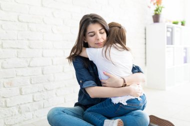 Çekici anne kucaklayan sevimli kız evde bakım