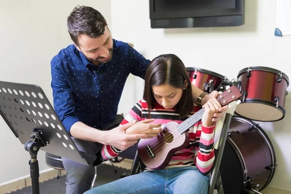 ヒスパニック系男性教師十代の女性を教える音楽学校ウクレレをプレイするには — ストック写真