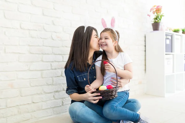 美丽的女人亲吻女儿在脸颊上 而拿着一篮节日鸡蛋在家里 — 图库照片