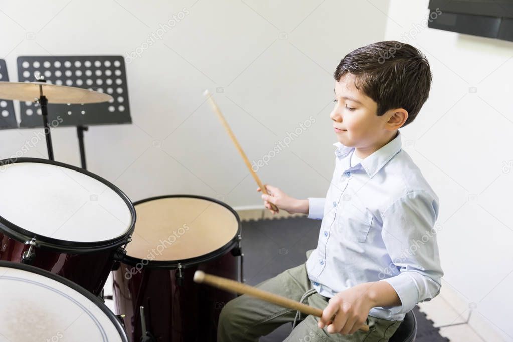 Caucasian boy learning to play drum in music class
