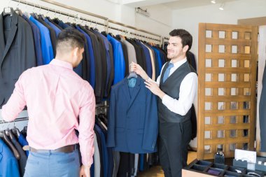 Takım elbise giyim mağazası müşteriye gösterilen genç erkek terzi