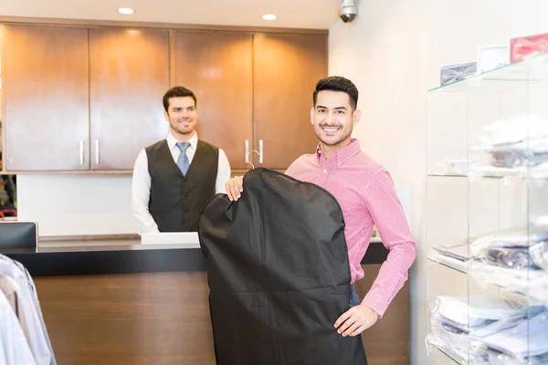 Male shopper smiling while holding cover of suit at rental shop