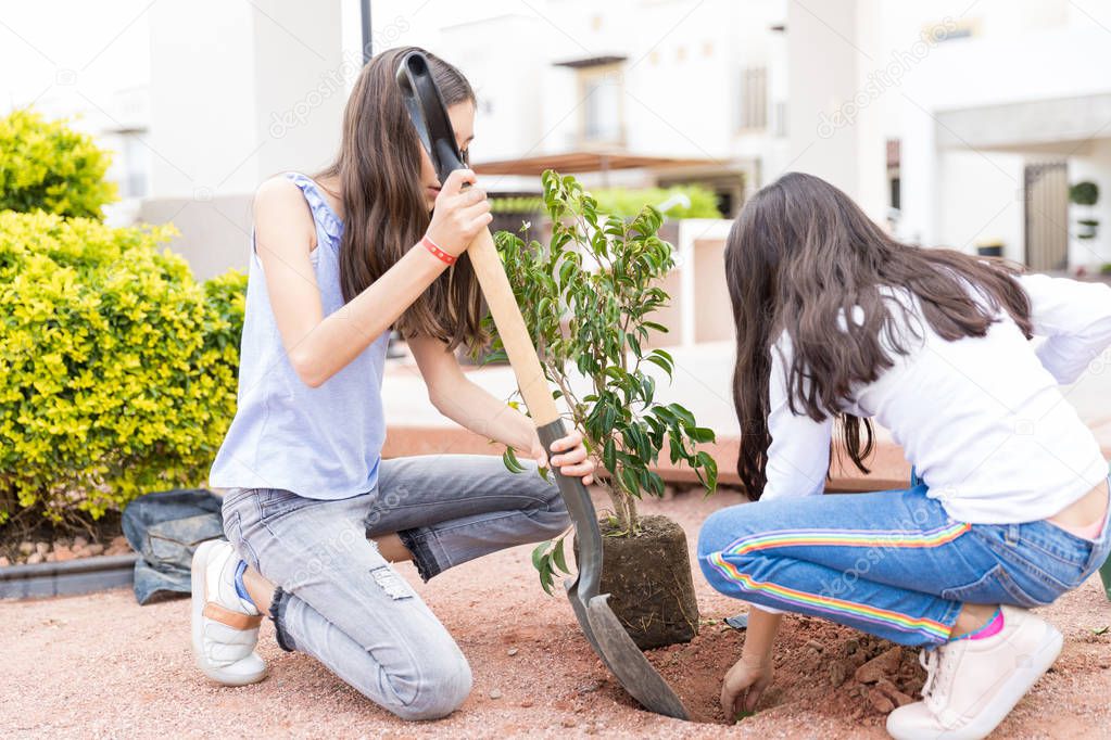Female gardeners digging a hole in the ground with shovel before planting