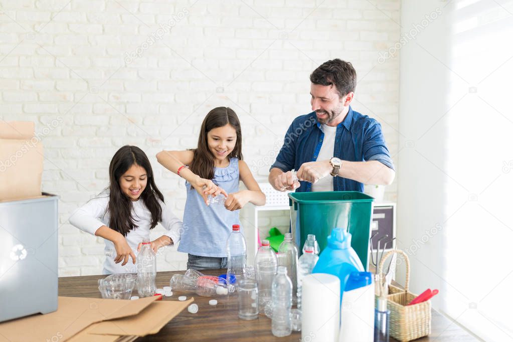 Father teaching daughters to crush the empty mineral water bottles before throwing them out