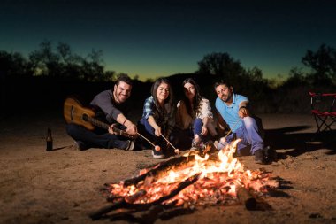 Genç erkek ve kadınların marshmallow şenlik ateşi, gece boyunca kavurma