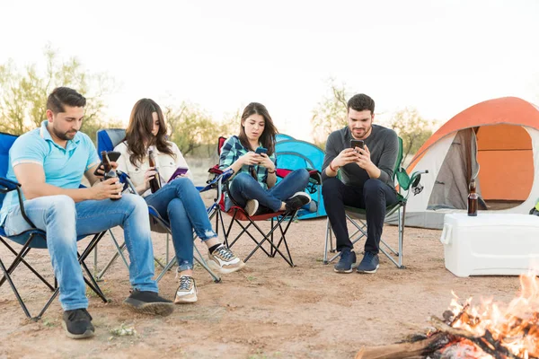 Full length of best buddies using mobile phones and destroying quality camping time