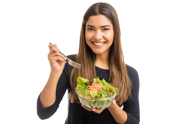 褐发女郎妇女通过在白色背景下吃沙拉来促进健康 — 图库照片