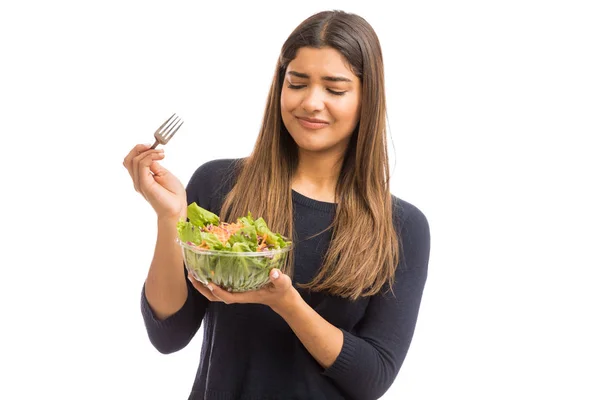 年轻的女士厌恶地看着绿色生菜沙拉在白色背景 — 图库照片