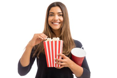 Beyaz arka plan üzerinde patlamış mısır tadını çıkarırken gülen esmer kadın portresi