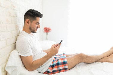 Adam yatakta otururken akıllı telefonda gelen bildirim okuma