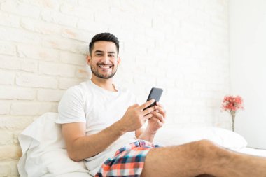 Yatak odasında akıllı telefonda yeni uygulama yükleme çekici adam portresi