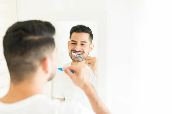 年轻人一边刷牙一边看着浴室的镜子里 — 图库照片