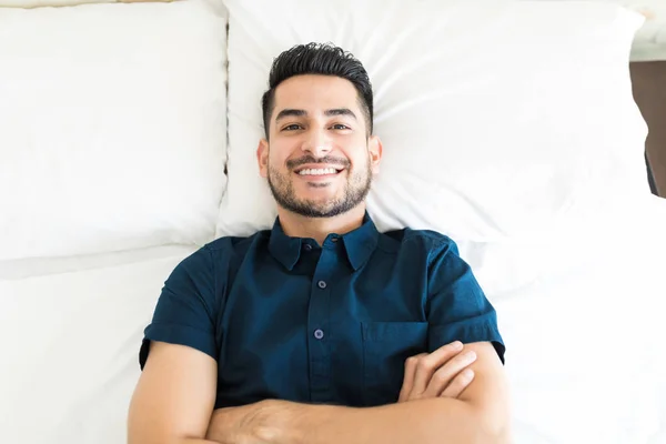 Confident handsome guy with arms crossed in bed